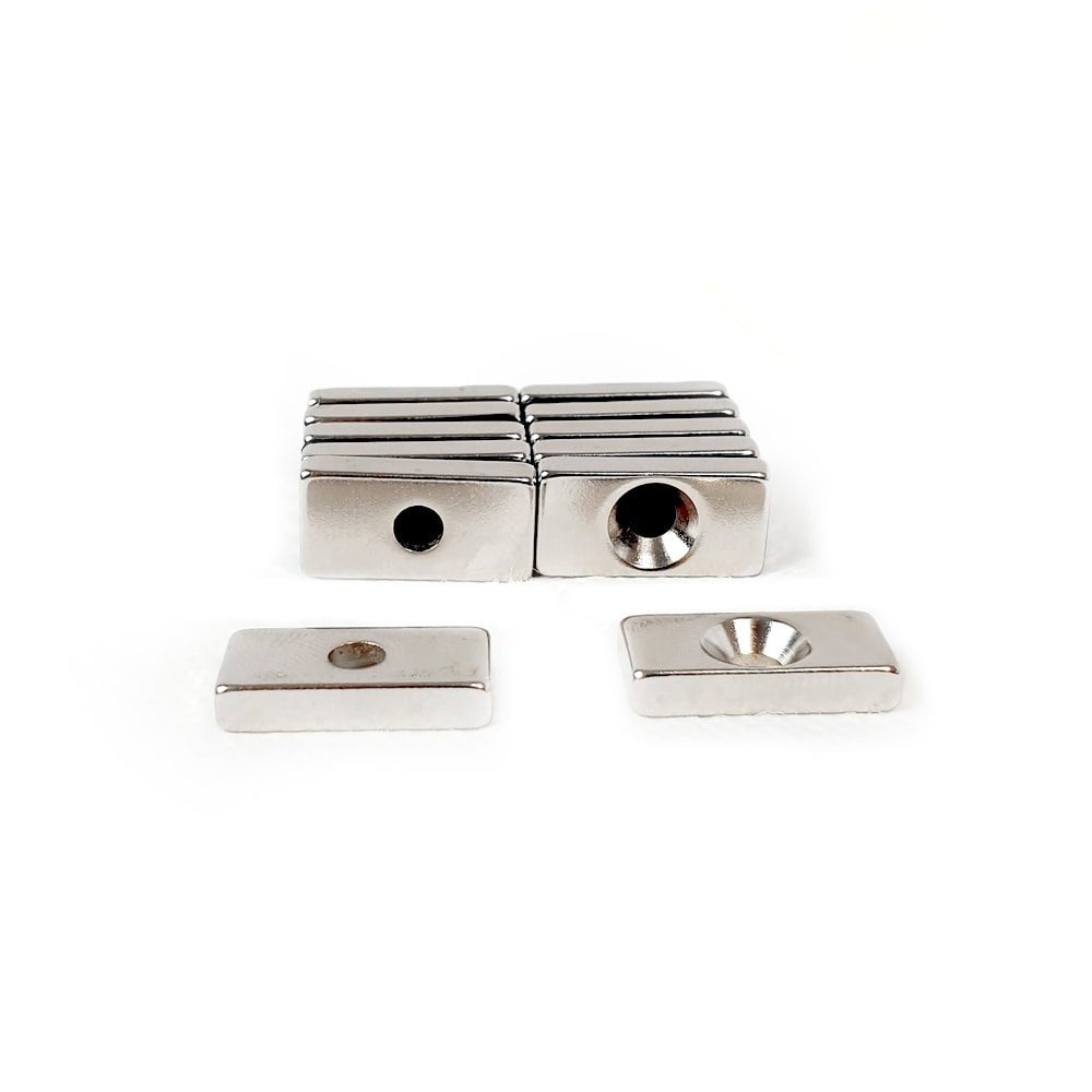 Rectangular Block Neodymium magnet with countersunk hole for screwing and with dimensions 20mm x 10mm x 4mm (4mm Hole), grade N42, featuring a nickel-copper-nickel coating and an 4.81KG pull force, commonly used in DIY, crafts, furniture design, fixings, kitchen design, lock mechanisms and science experiments.