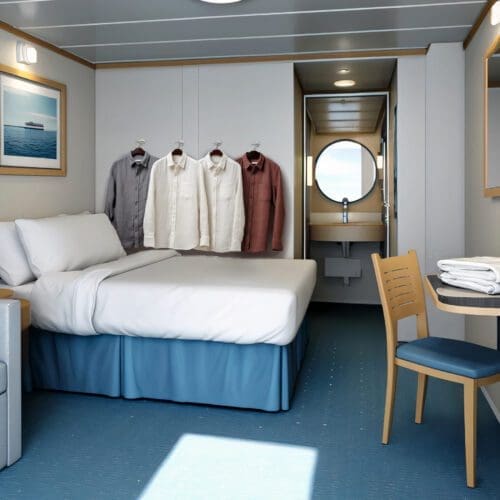 Cruise ship room with bed, bathroom and hanging clothes.